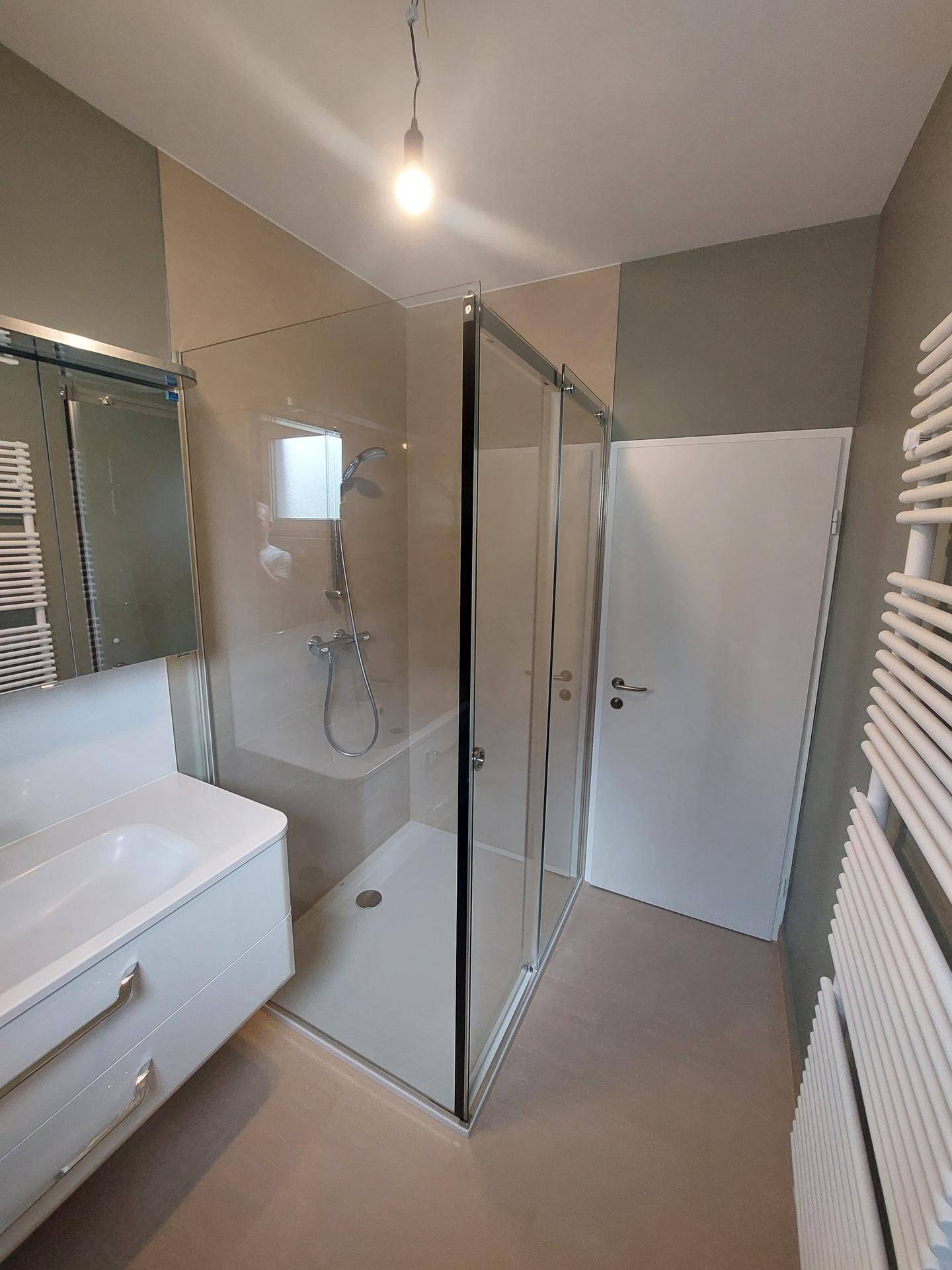 Helles Badezimmer mit Glasduschkabine, modernem Waschtisch und Fliesenboden.