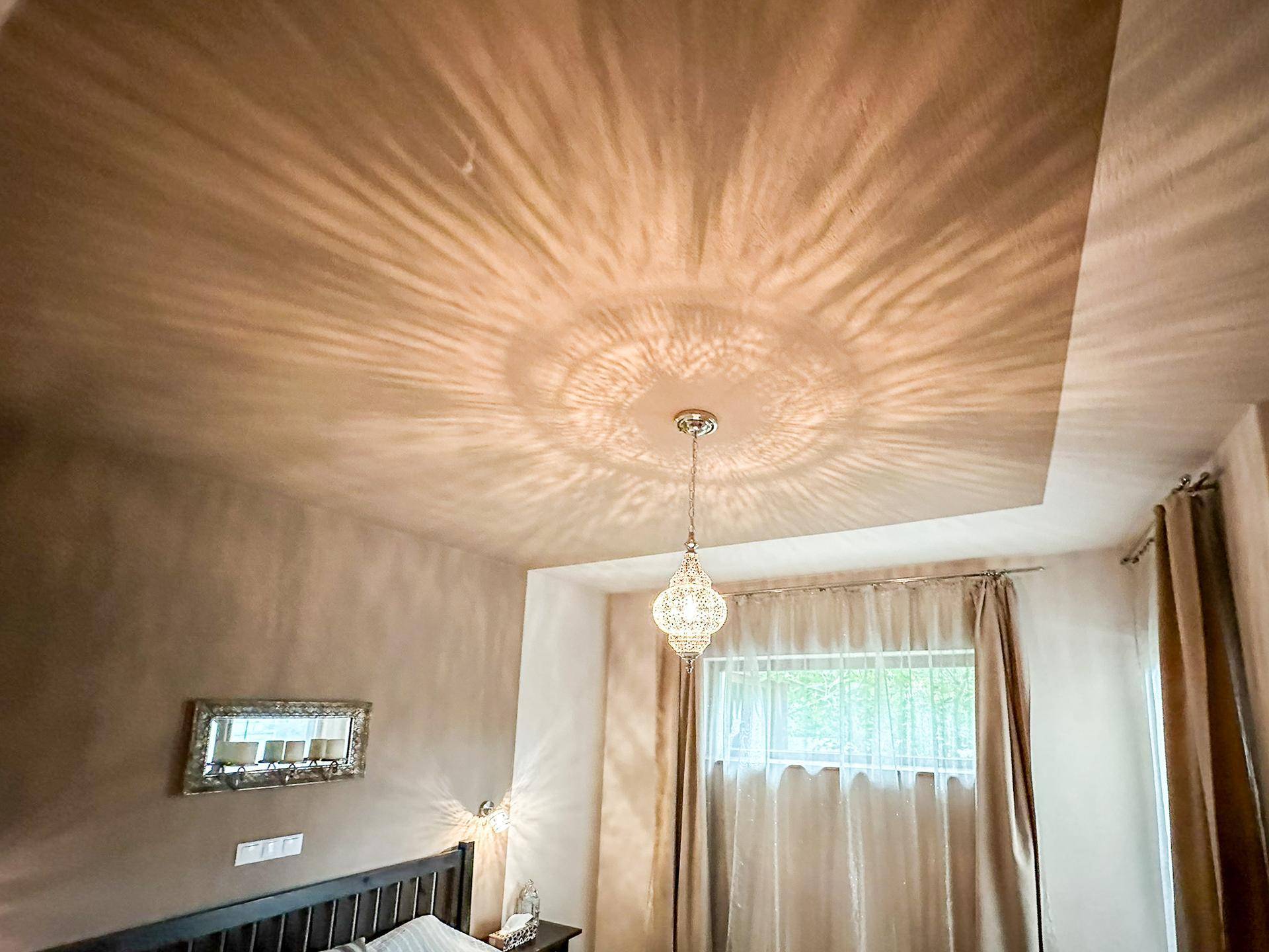 Deckenansicht im Schlafzimmer mit dekorativer Beleuchtung und Vorhängen.