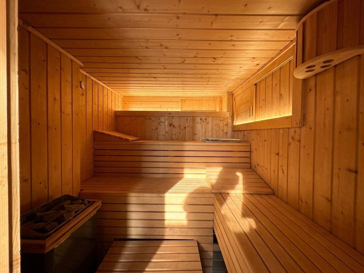Gemütliche Holzsauna mit mehreren Bänken und indirekter Beleuchtung für Entspannung.