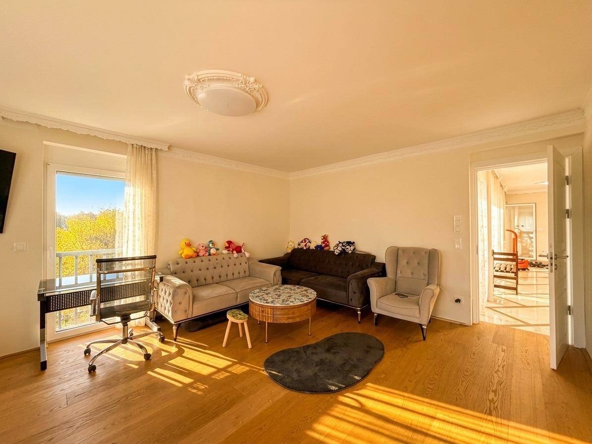 Helles Wohnzimmer mit Holzboden, gemütlichen Sofas und Zugang zu einem Balkon.