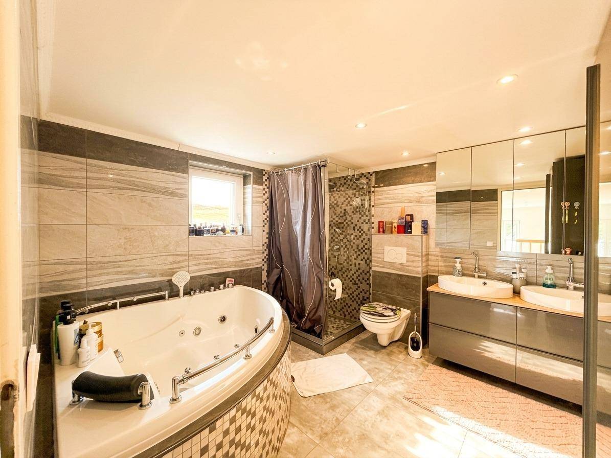 Modernes Badezimmer mit Whirlpool-Badewanne, großer Dusche und Doppelwaschbecken.