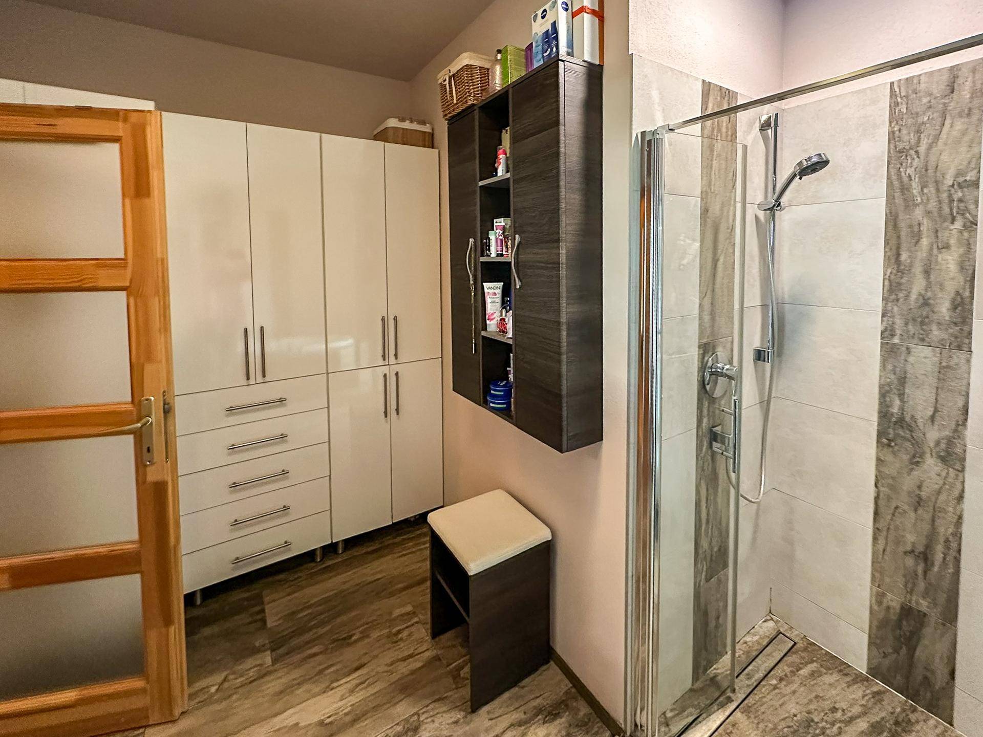 Modernes Badezimmer mit Duschkabine, Einbauschränken und Fliesenboden.