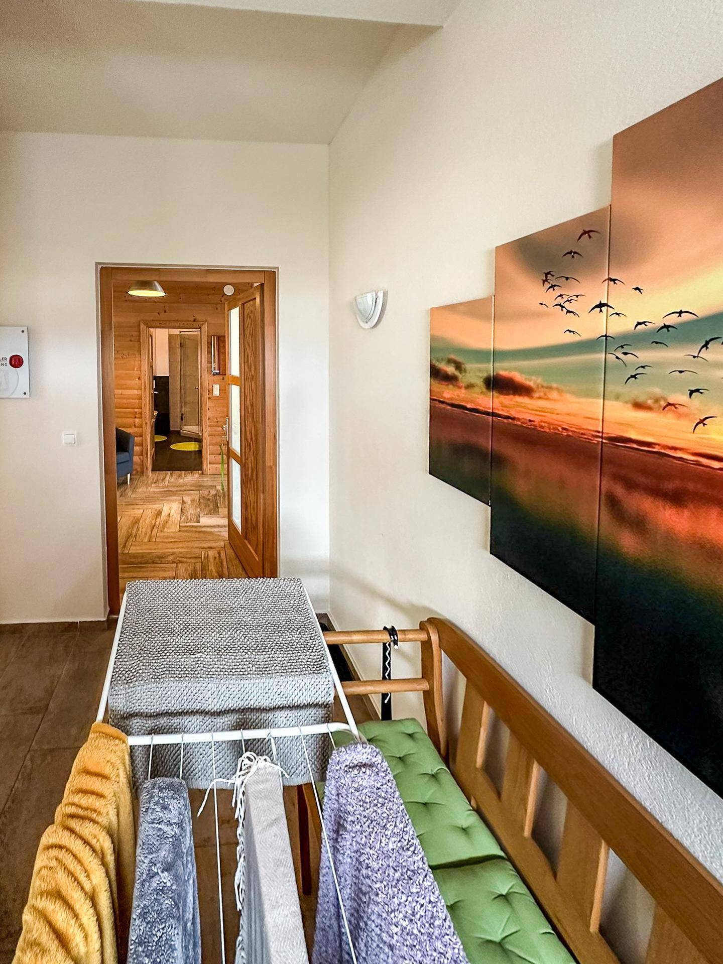Heller Flur mit Holzboden, einer Sitzbank und Wandkunst, die einen Sonnenuntergang darstellt.
