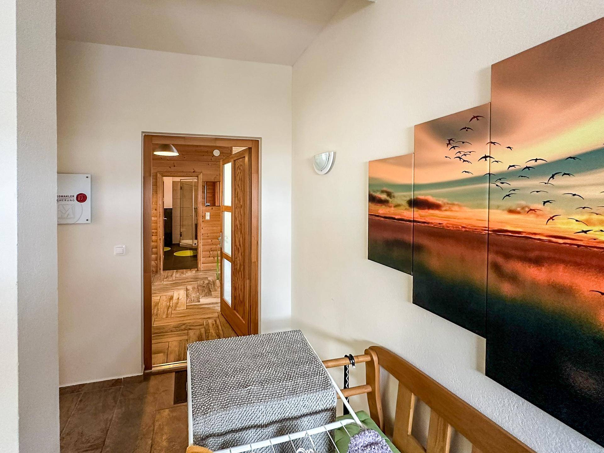 Geräumiger Flur mit Holzboden und einer großen Wanddekoration, die einen Sonnenuntergang zeigt.