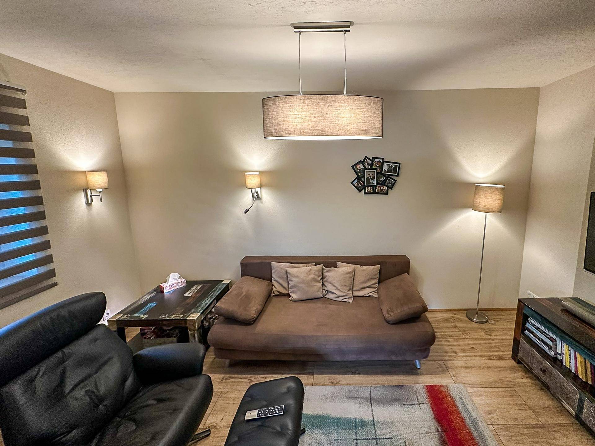 Gemütliches Wohnzimmer mit Sofa, Sessel und indirekter Beleuchtung.