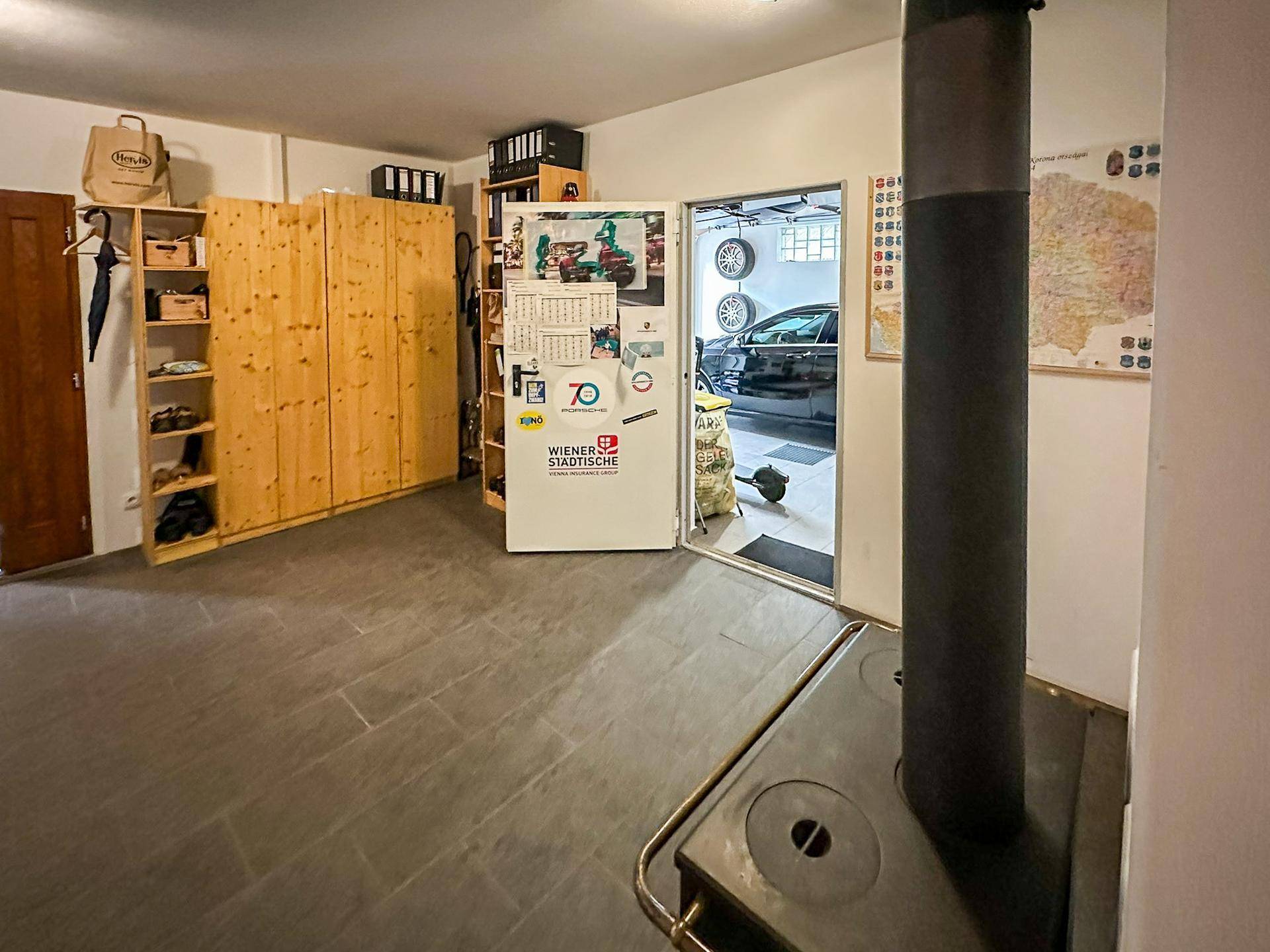 Kellerraum mit Holzschränken, Kaminofen und Zugang zur Garage, ideal als Abstell- oder Hobbyraum.