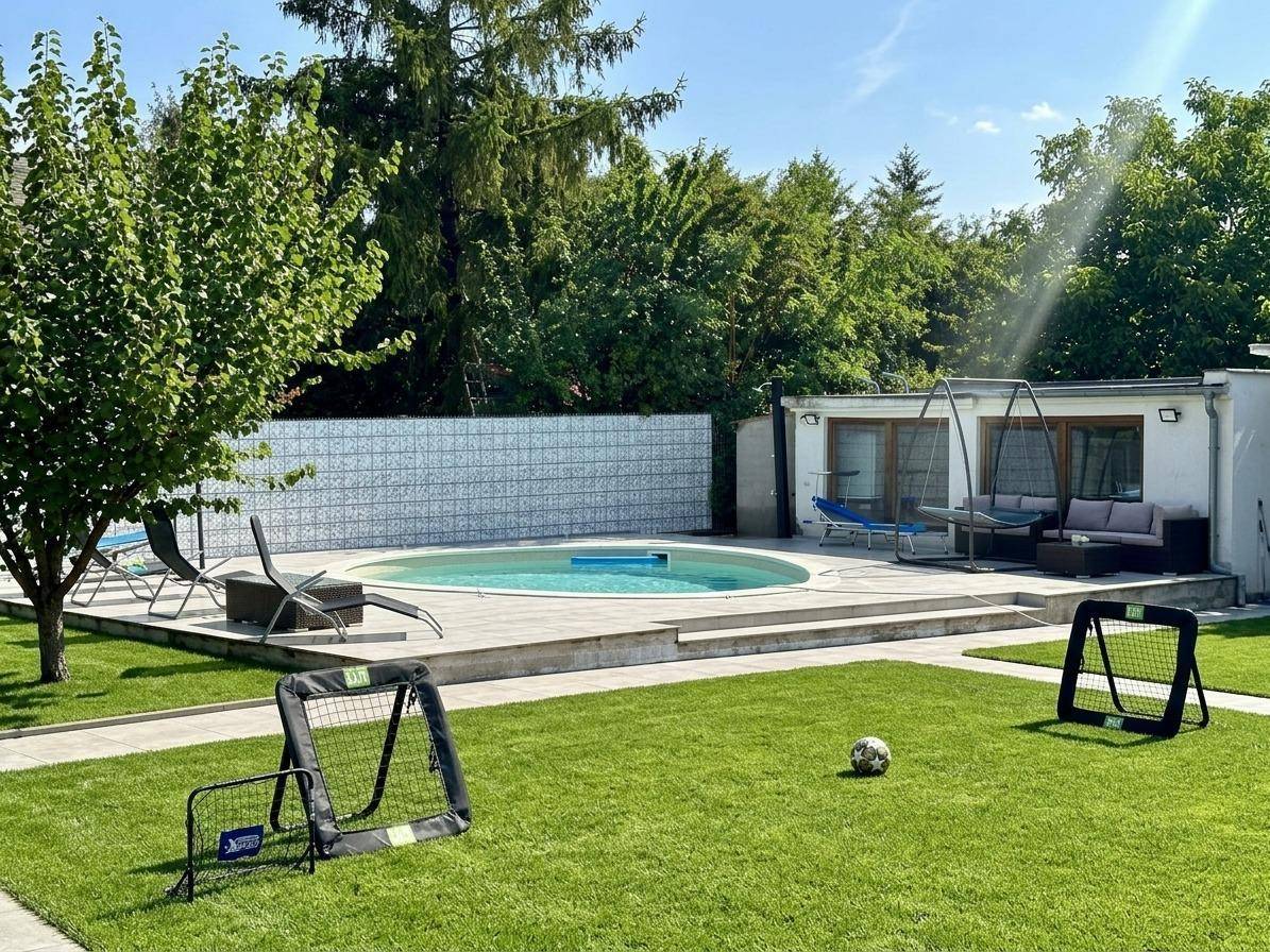 Gepflegter Gartenbereich mit ovalem Swimmingpool, Rasenfläche und Fußballtoren.