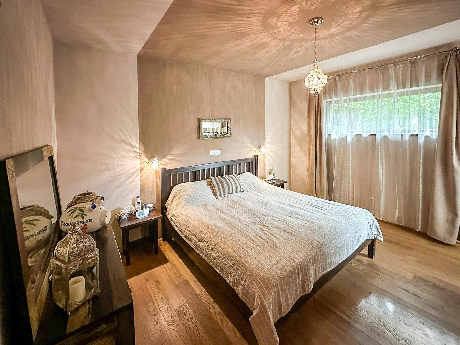 Gemütliches Schlafzimmer mit Doppelbett, Holzboden und dekorativer Deckenbeleuchtung.