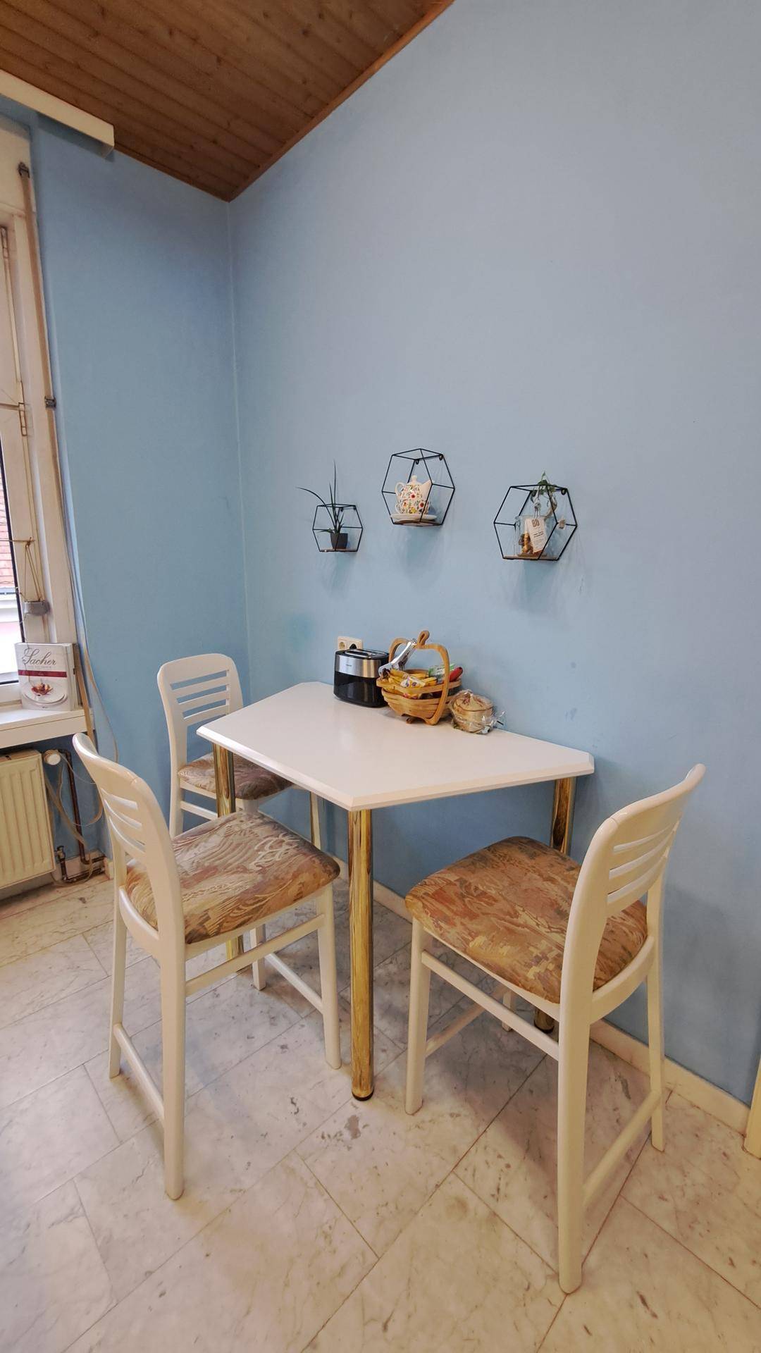 Kleiner, gemütlicher Essbereich in der Küche mit einem weißen Tisch und Stühlen vor blauen Wänden.