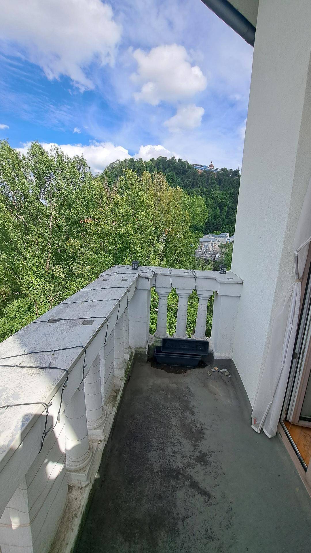 Kleiner Balkon mit Balustrade und weitem Blick ins Grüne und auf die umliegende Hügellandschaft.