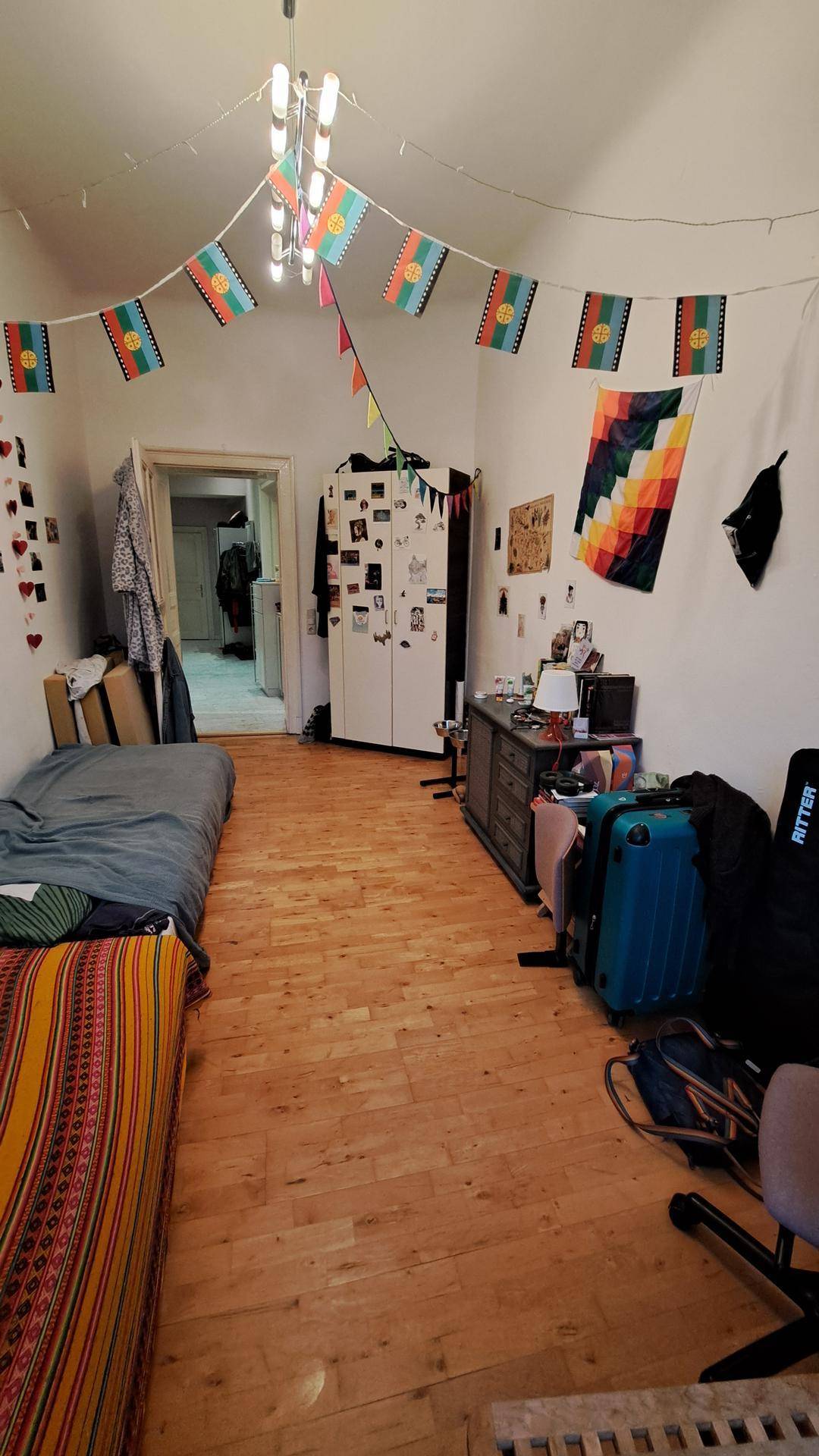 Zimmer mit Holzboden, Einzelbett und einem weißen Kleiderschrank, der viel Stauraum bietet.