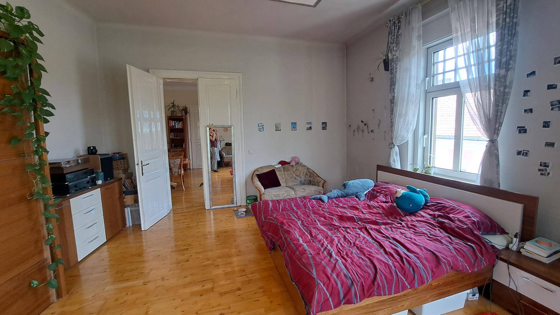 Helles Schlafzimmer mit Holzboden, Doppelbett und einem großen Spiegel, der den Raum optisch erweitert.