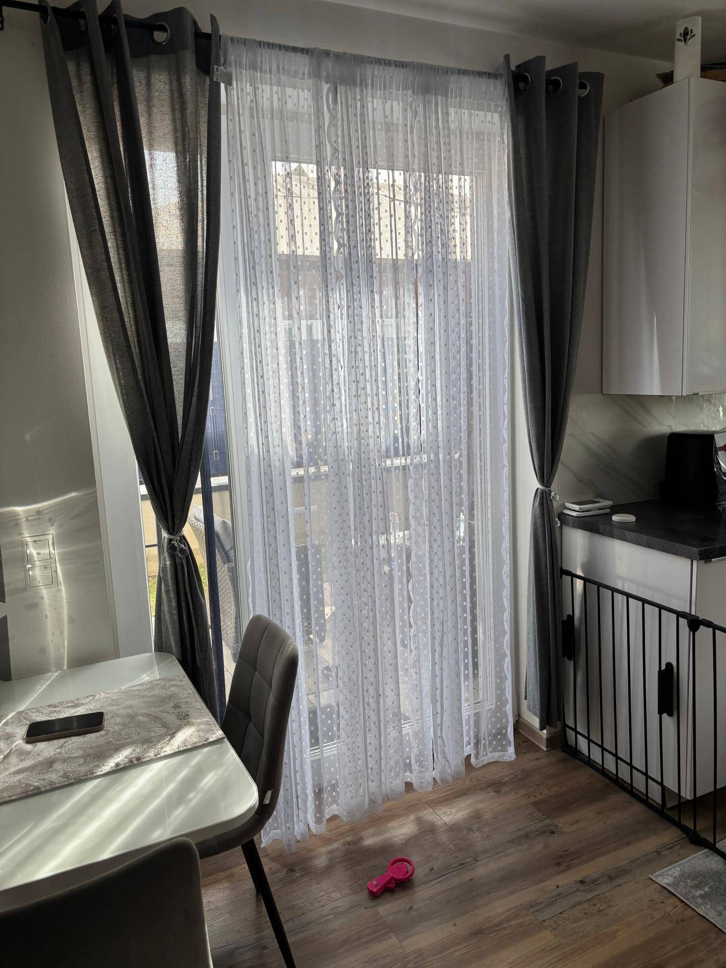 Große Fenstertür mit Vorhängen, die viel Tageslicht in den Wohnbereich lässt.