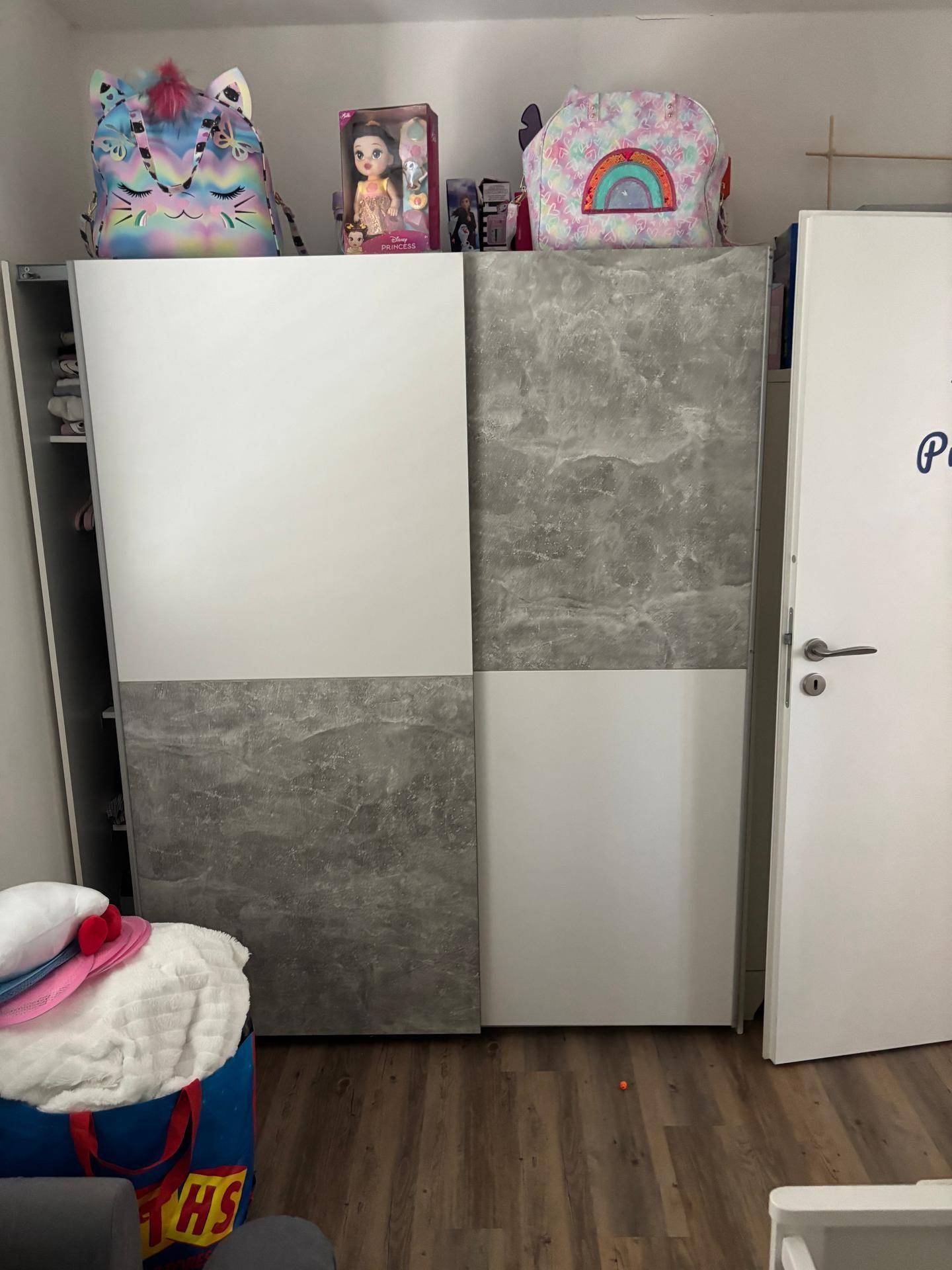 Großer Kleiderschrank mit modernen grauen und weißen Fronten in einem Kinderzimmer.