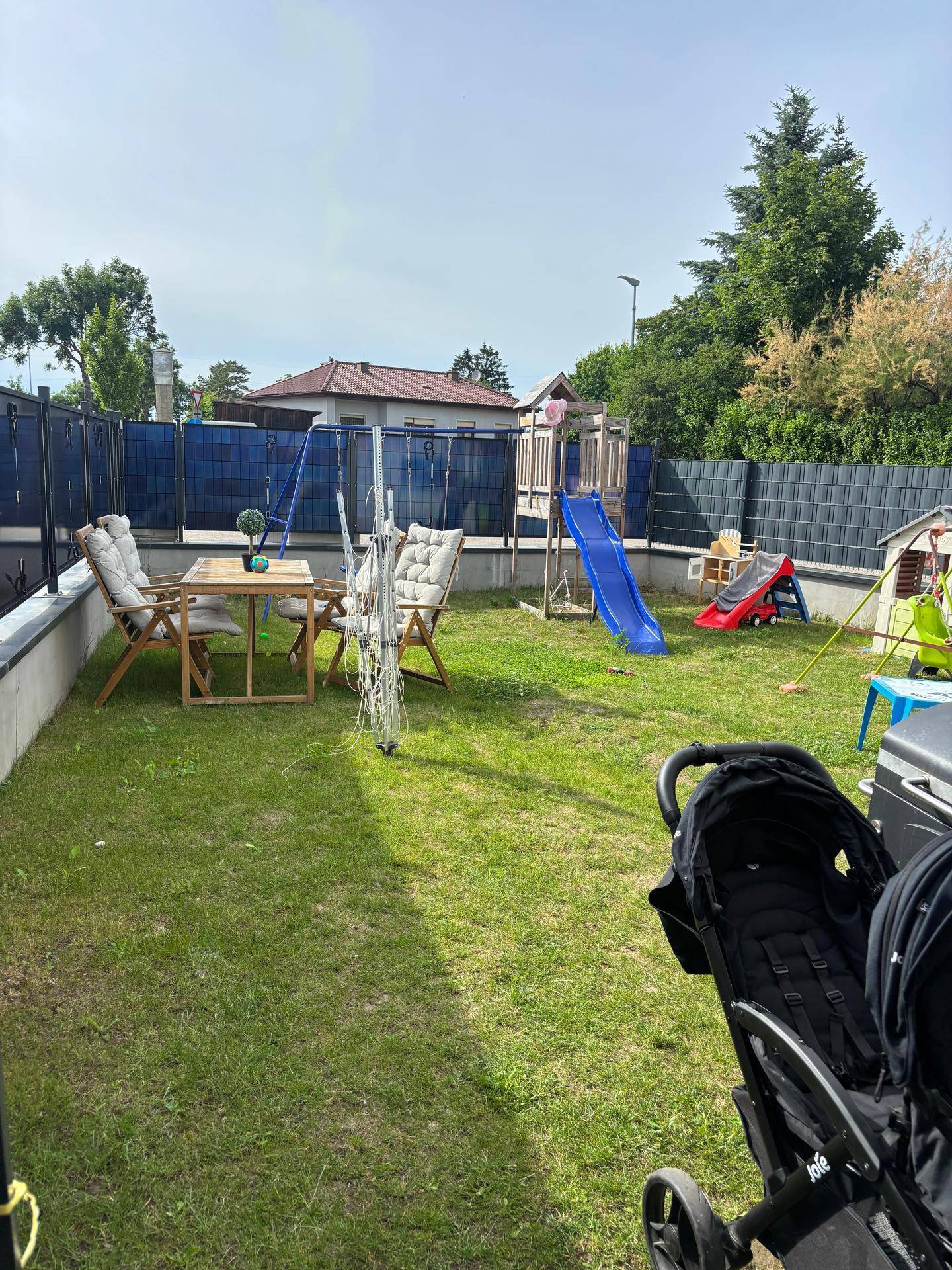 Großer Garten mit Rasenfläche, Kinderspielgeräten und einem Esstisch im Freien.