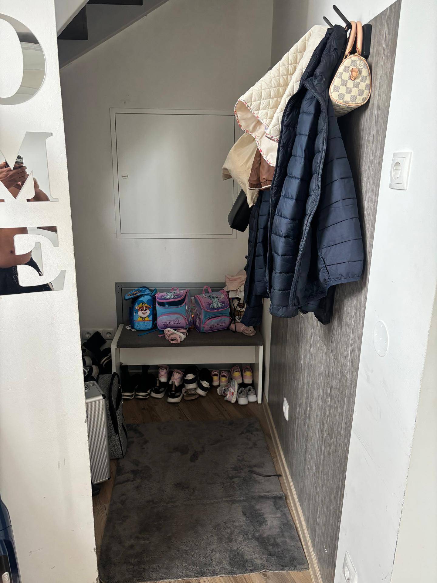Eingangsbereich unter der Treppe mit Garderobe, Schuhablage und modernem Design.