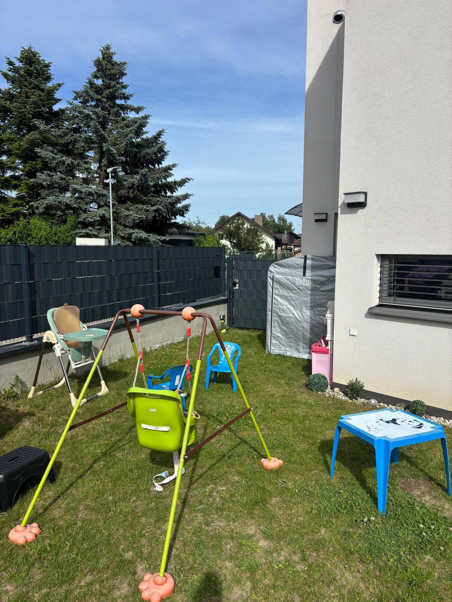 Gartenbereich mit Kinderschaukel, kleinem Tisch und Blick auf das Haus.