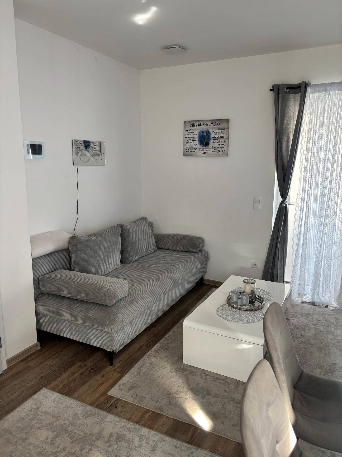 Gemütlicher Wohnbereich mit grauem Sofa, weißem Couchtisch und hellem Teppich.