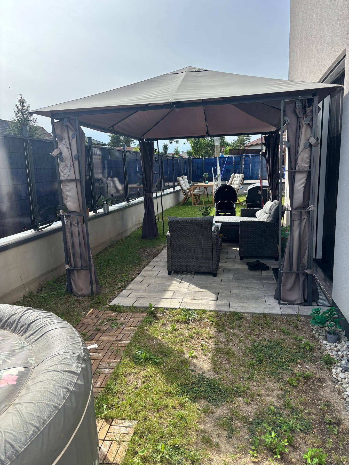 Gemütlicher Gartenbereich mit überdachtem Sitzplatz, Rasenfläche und Whirlpool.