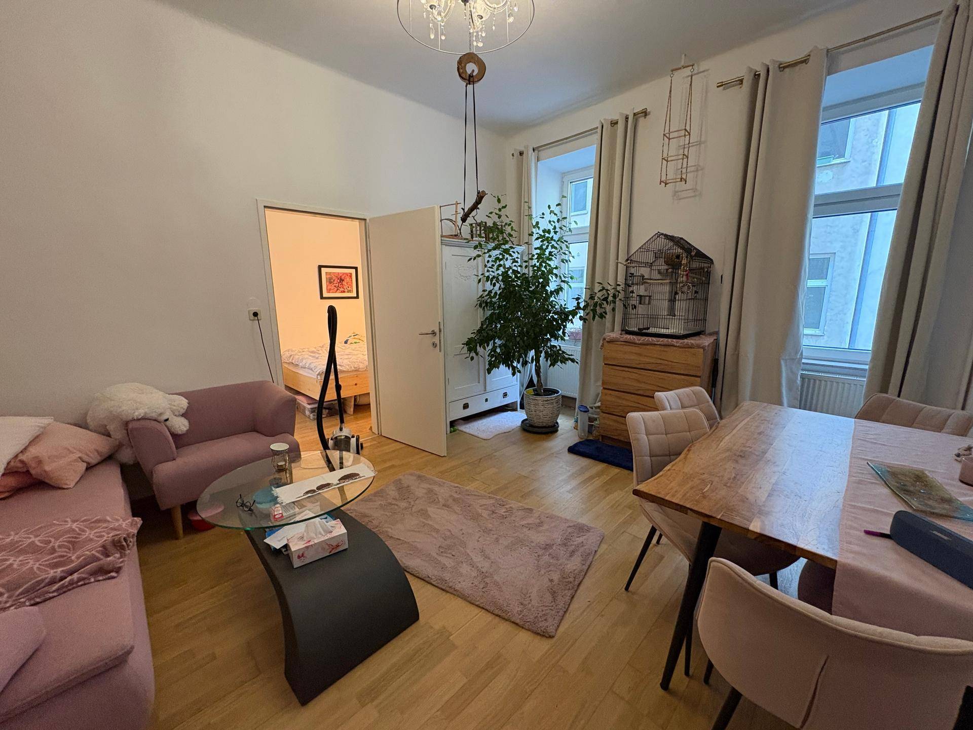 Gemütlicher Wohn-Essbereich mit rosa Sofa, Esstisch und großen Fenstern für viel Tageslicht.