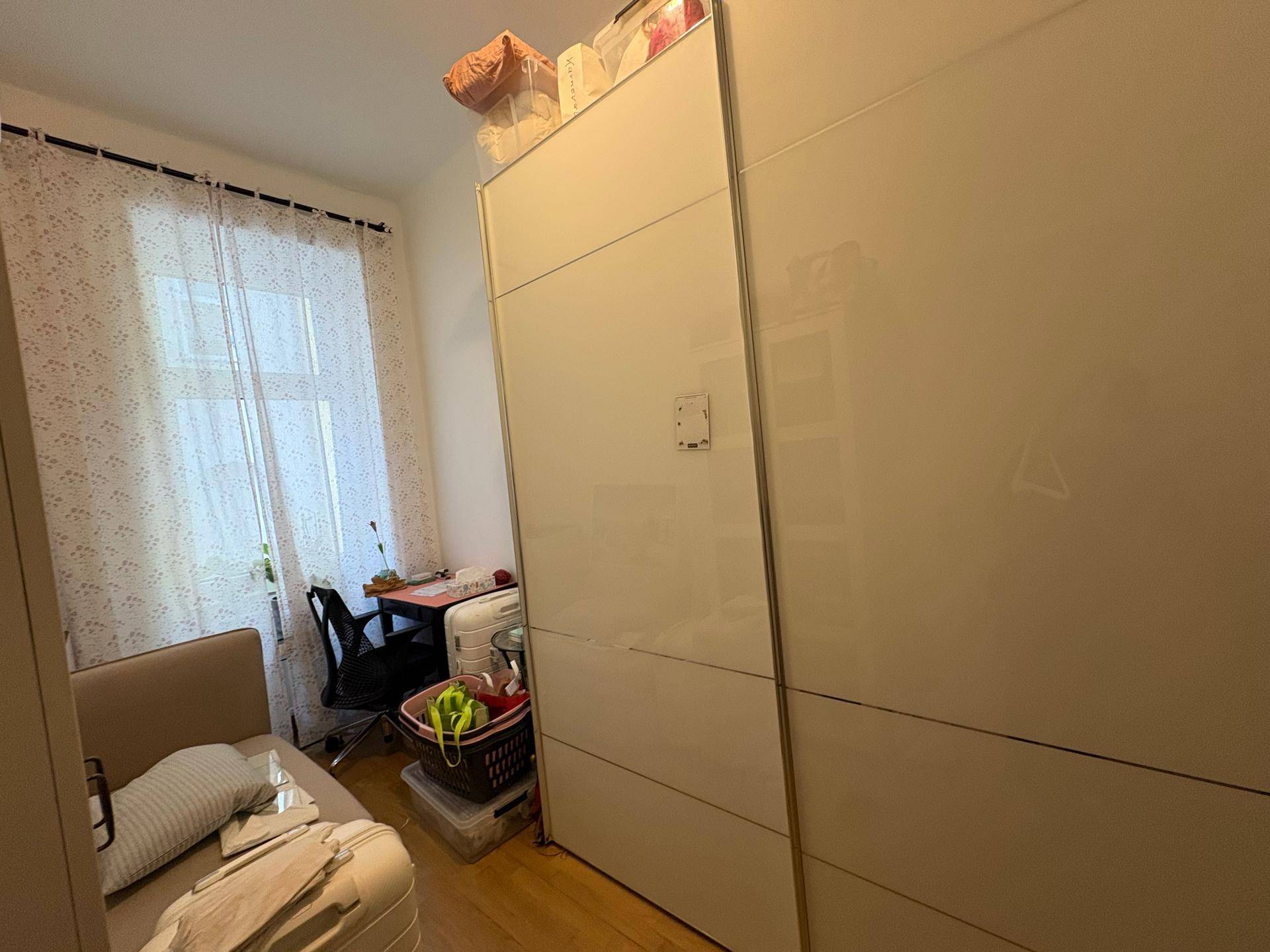 Schlafzimmer mit Bett, Schreibtisch und großen, modernen Schiebetürenschränken für viel Stauraum.