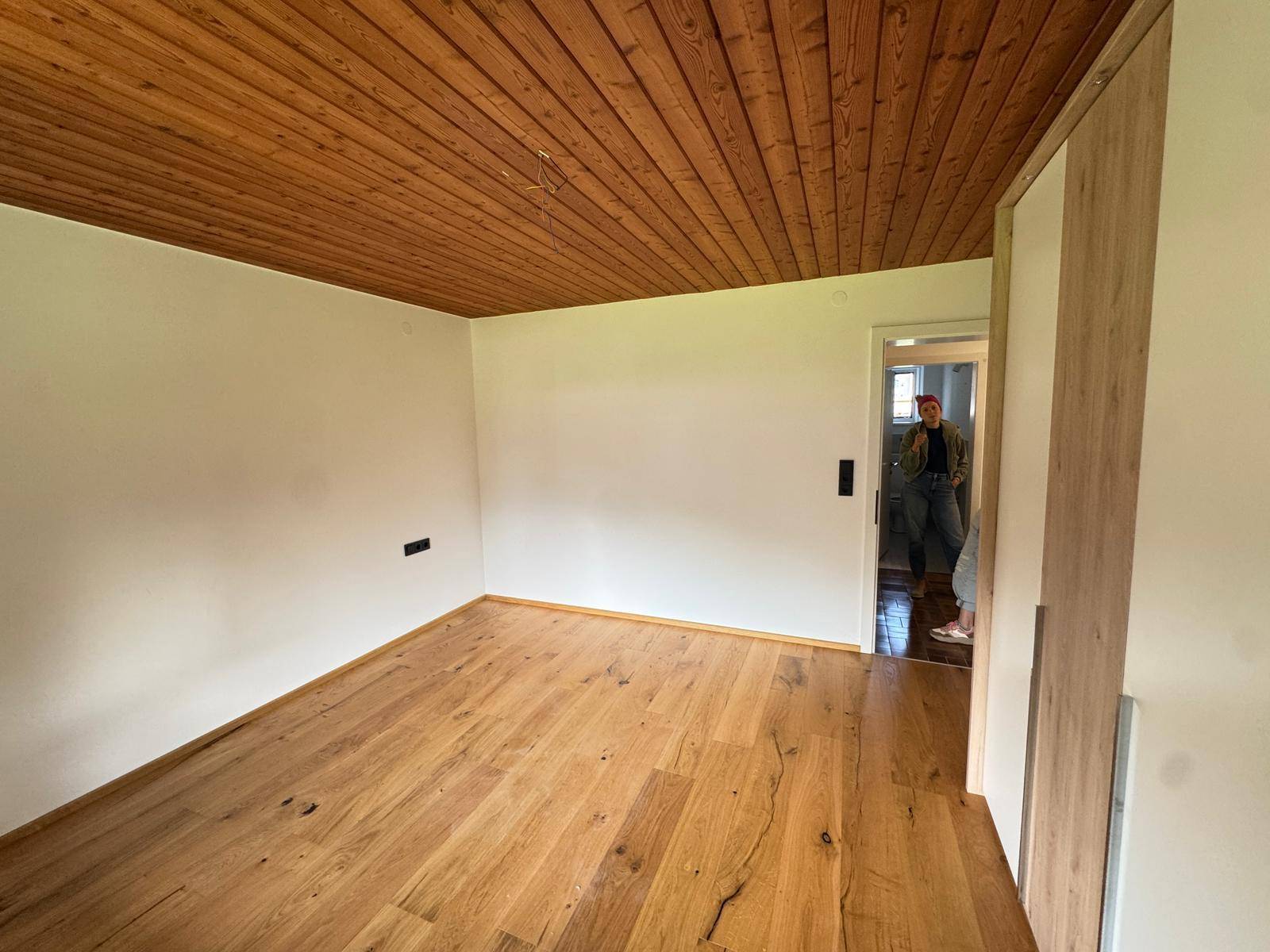 Gemütliches Zimmer mit Holzdielenboden und einer warmen Holzdecke, die eine behagliche Atmosphäre schafft.