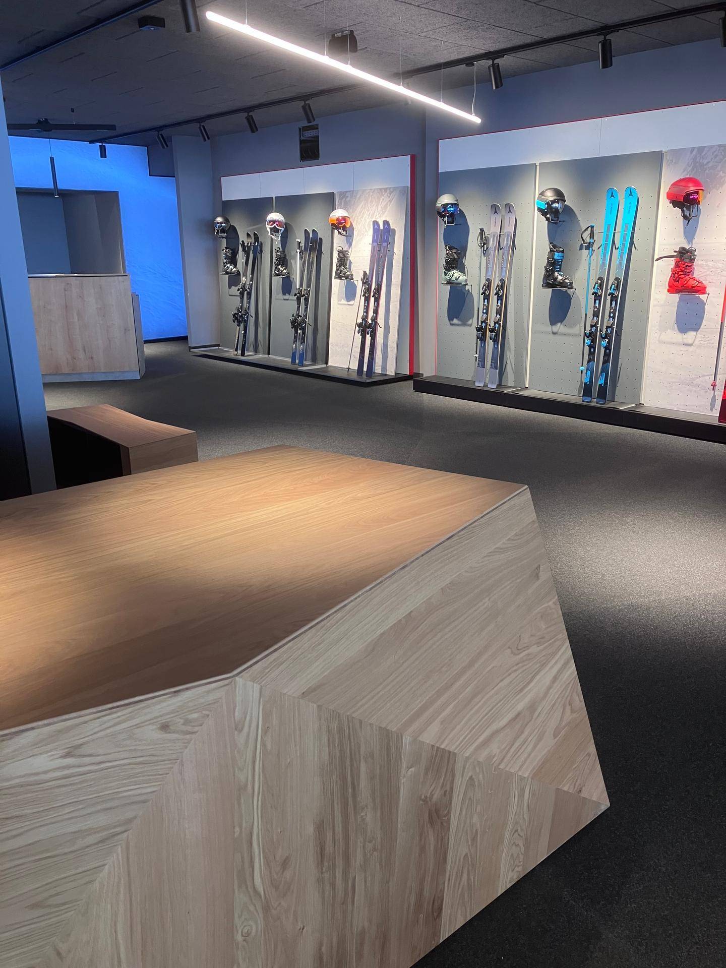 Blick über die Holztheke auf die Skiauslagen und den modernen Verkaufsraum mit Teppichboden.