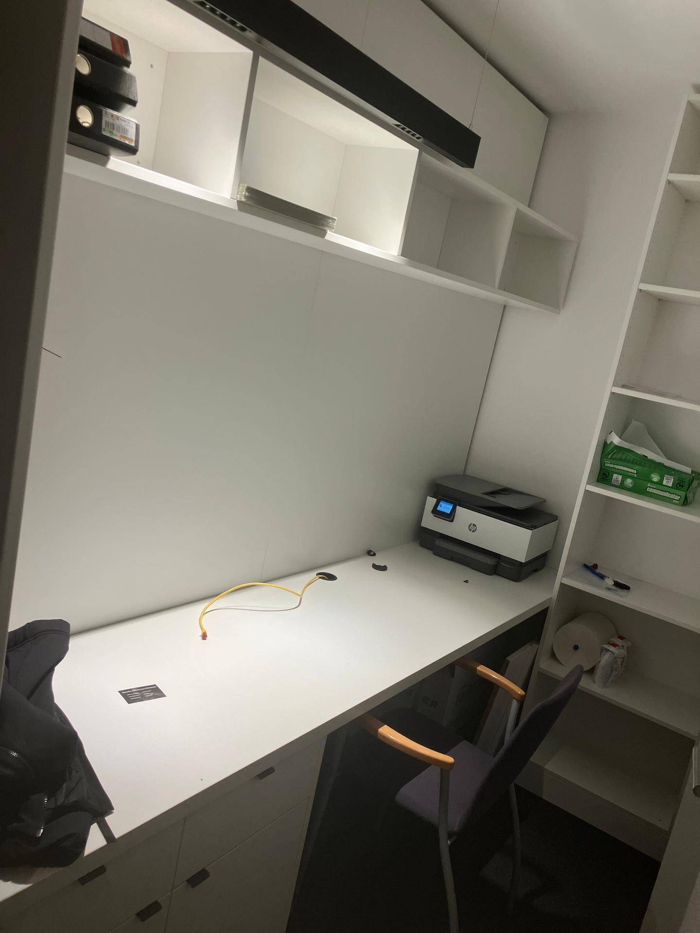 Heller Bürobereich mit integriertem Schreibtisch, Wandregalen und einem Drucker für effizientes Arbeiten.