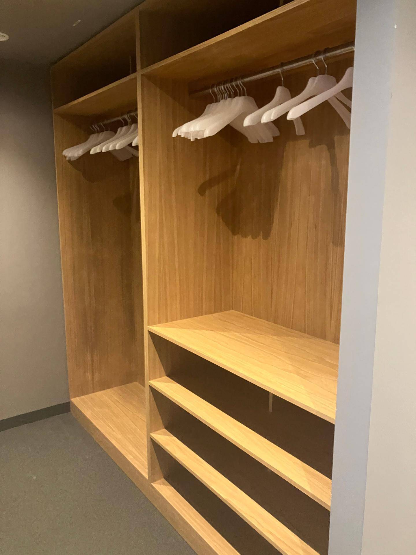 Geräumiger begehbarer Kleiderschrank aus hellem Holz mit Kleiderstangen und offenen Regalfächern.