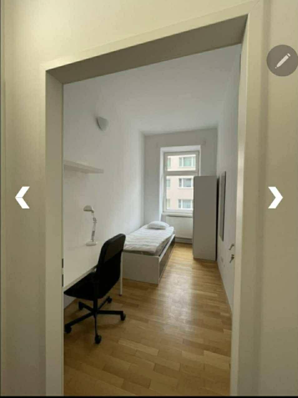 Langes, helles Schlafzimmer mit Fenster, Einzelbett und Arbeitsbereich.