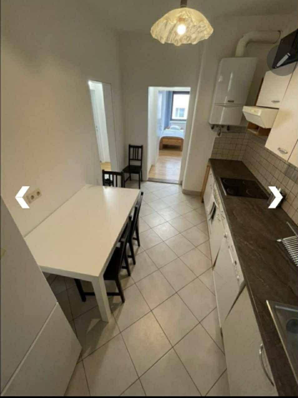 Schmale Küche mit Essbereich, Einbauküche und Blick in den angrenzenden Raum.