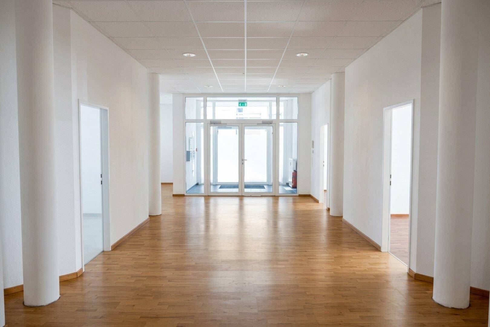 Heller und geräumiger Flur mit Holzboden und Zugang zu mehreren Büroräumen in einem modernen Gebäude.