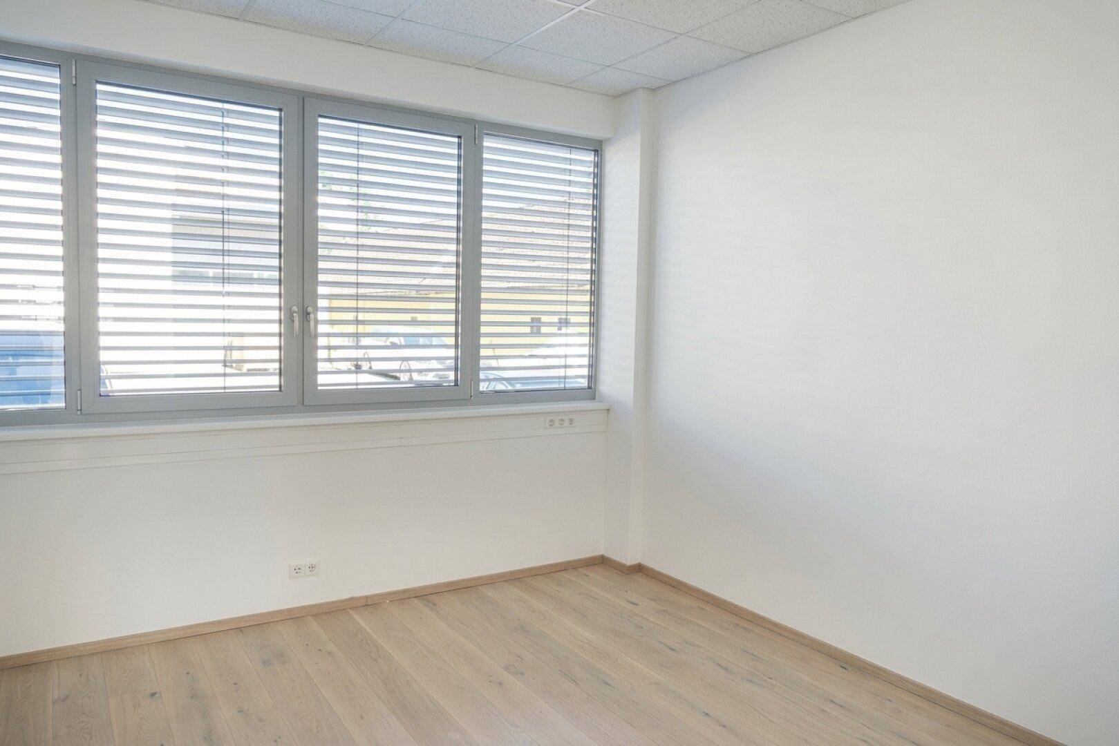 Helle Büroecke mit Fenster und Jalousien, ideal für einen Arbeitsplatz mit viel Tageslicht.