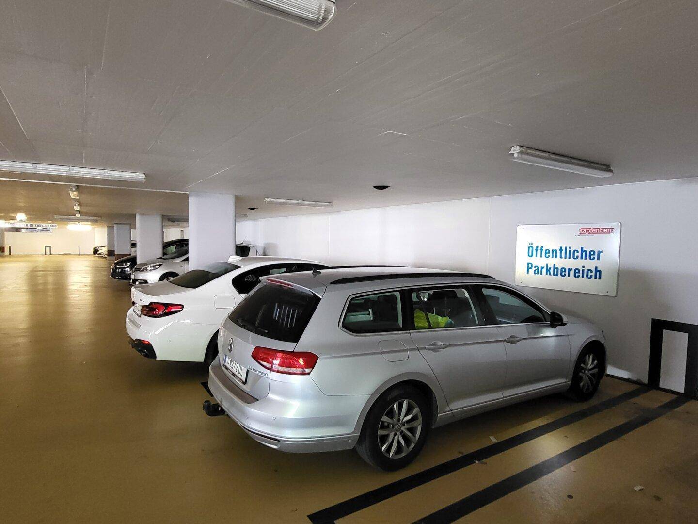 Tiefgarage mit geparkten Fahrzeugen und Beschilderung für den öffentlichen Parkbereich.