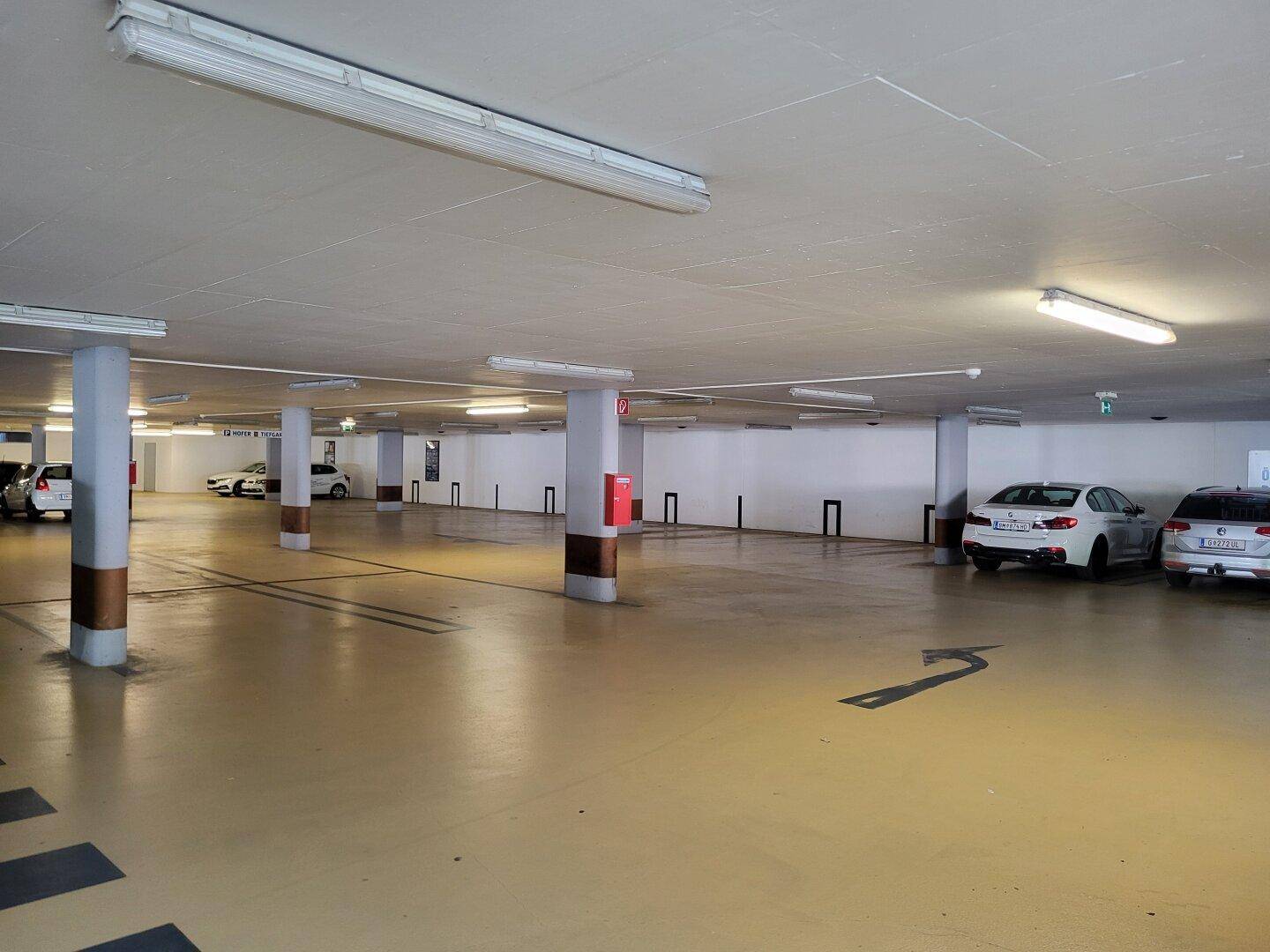 Geräumige Tiefgarage mit vielen freien Stellplätzen und klaren Fahrbahnmarkierungen.