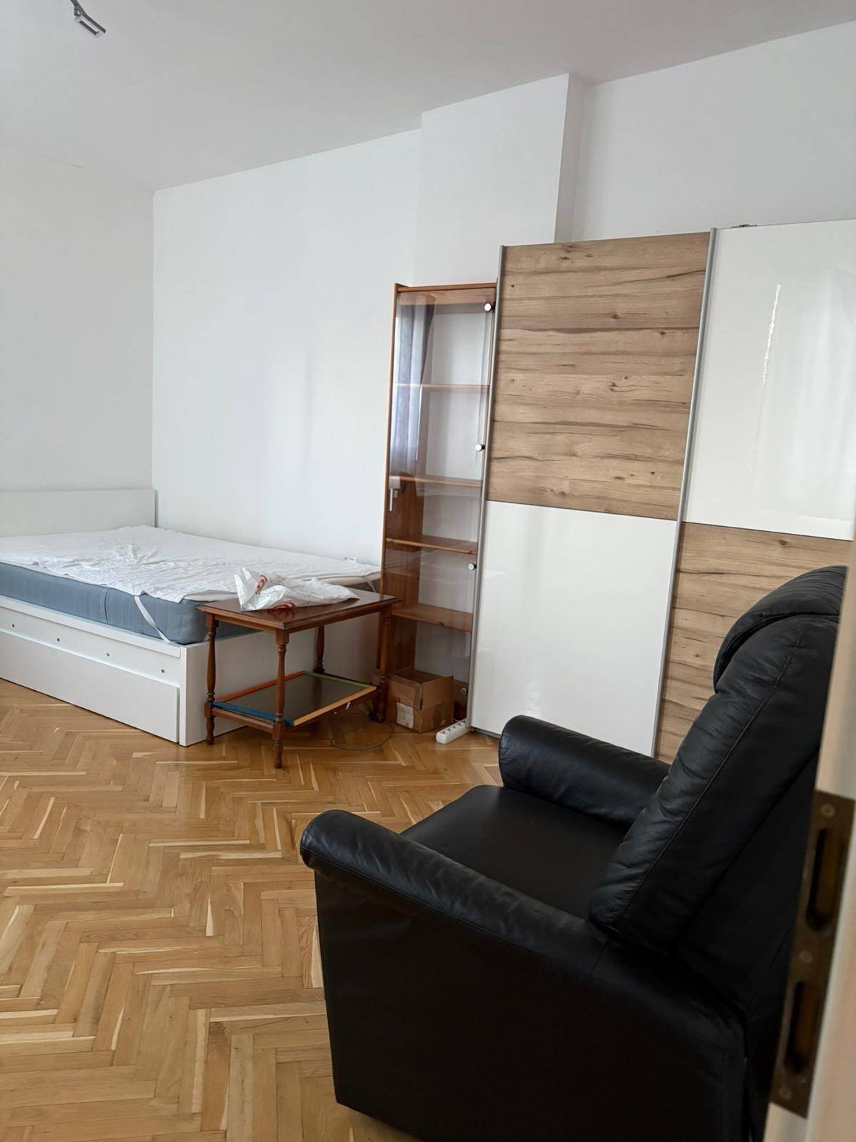 Geräumiges Zimmer mit Parkettboden, Bett und Schrank, bietet vielseitige Nutzungsmöglichkeiten.