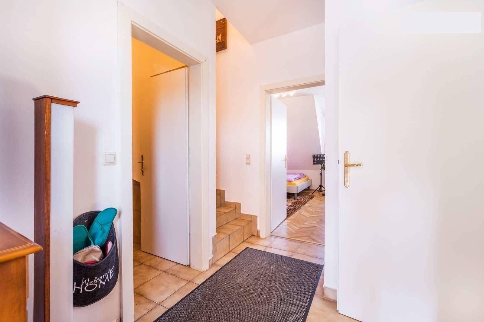 Heller Flur mit Fliesenboden und Treppenaufgang, der zu weiteren Räumen führt.