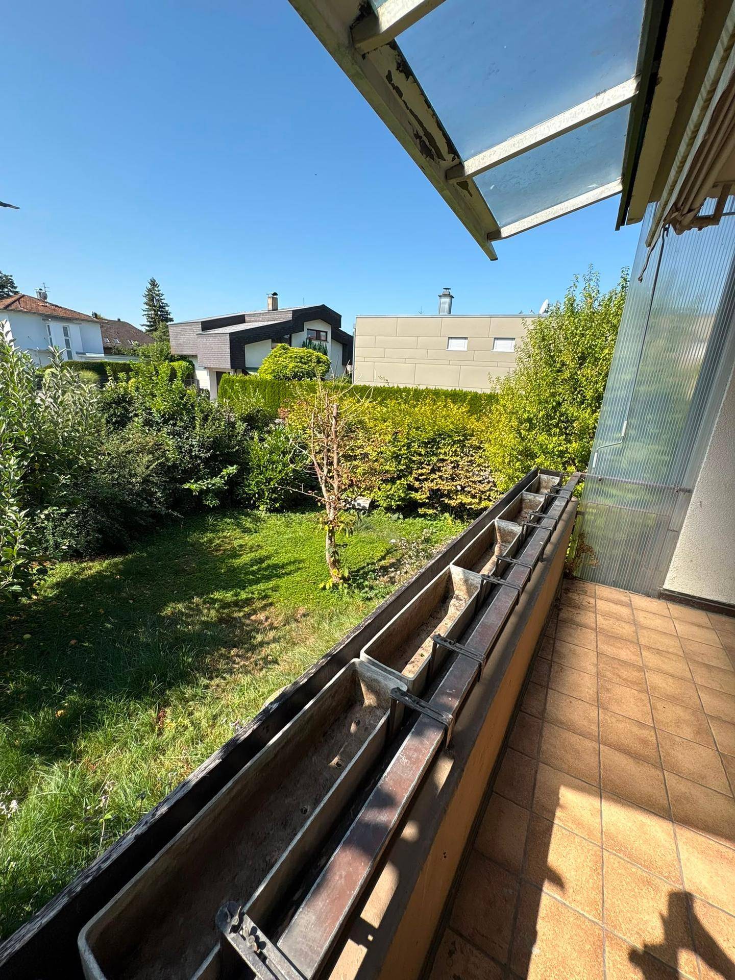 Balkon mit Fliesenboden, Blumenkästen und einem schönen Blick auf den grünen Garten.