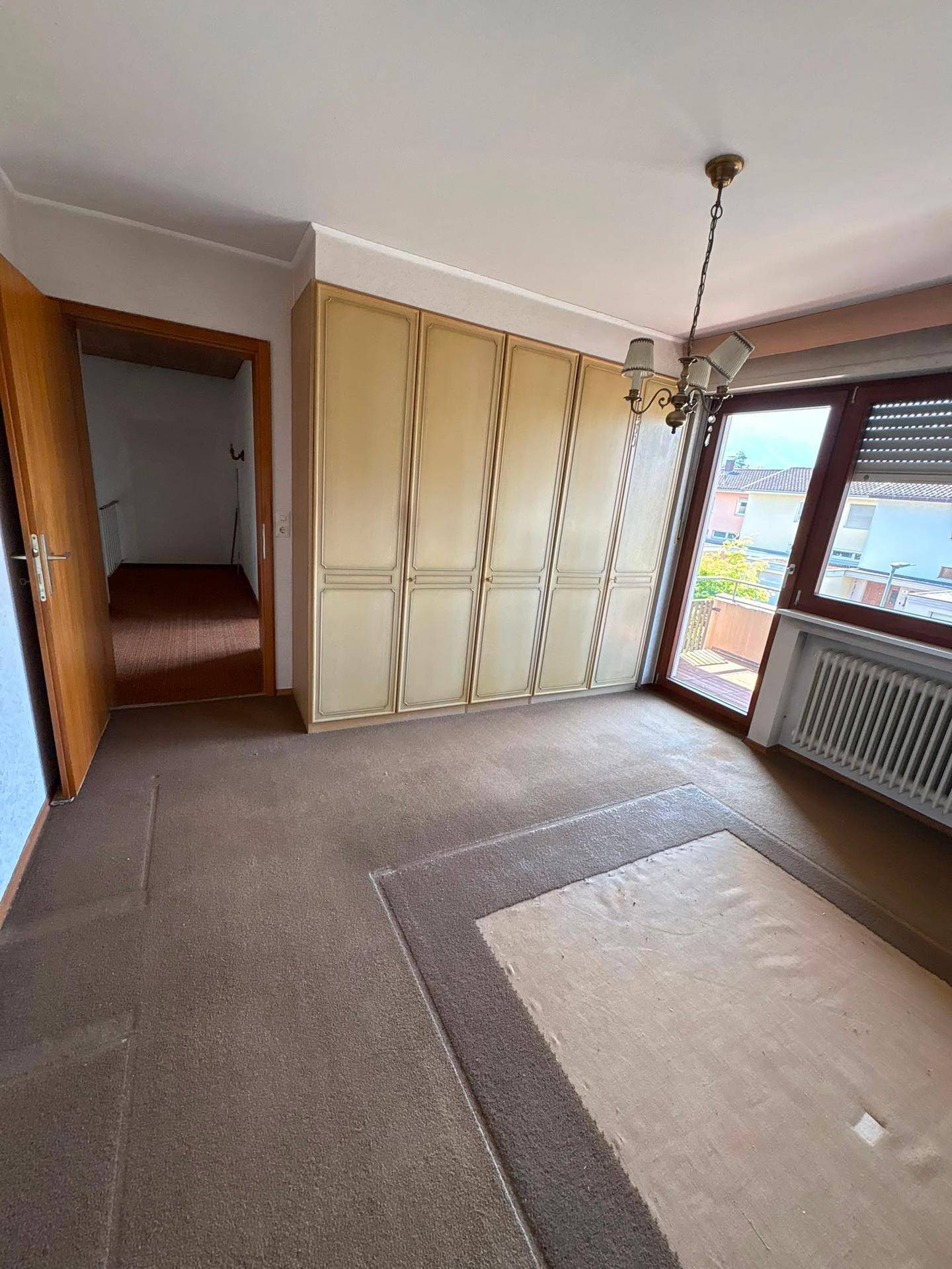 Schlafzimmer mit großem Einbauschrank, Teppichboden und Zugang zum Balkon, hell und geräumig.