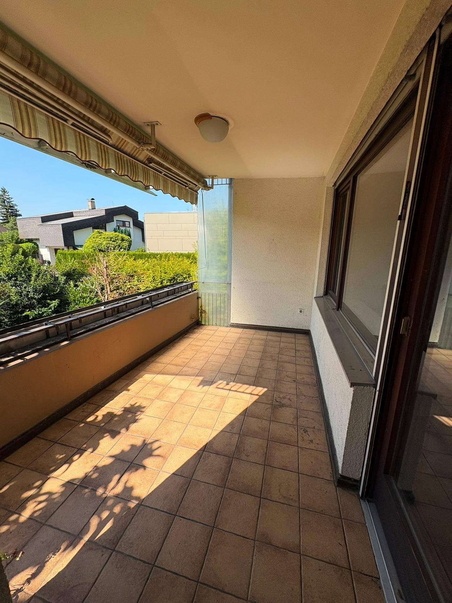 Geräumiger Balkon mit Fliesenboden und Markise, bietet einen sonnigen Platz im Freien.