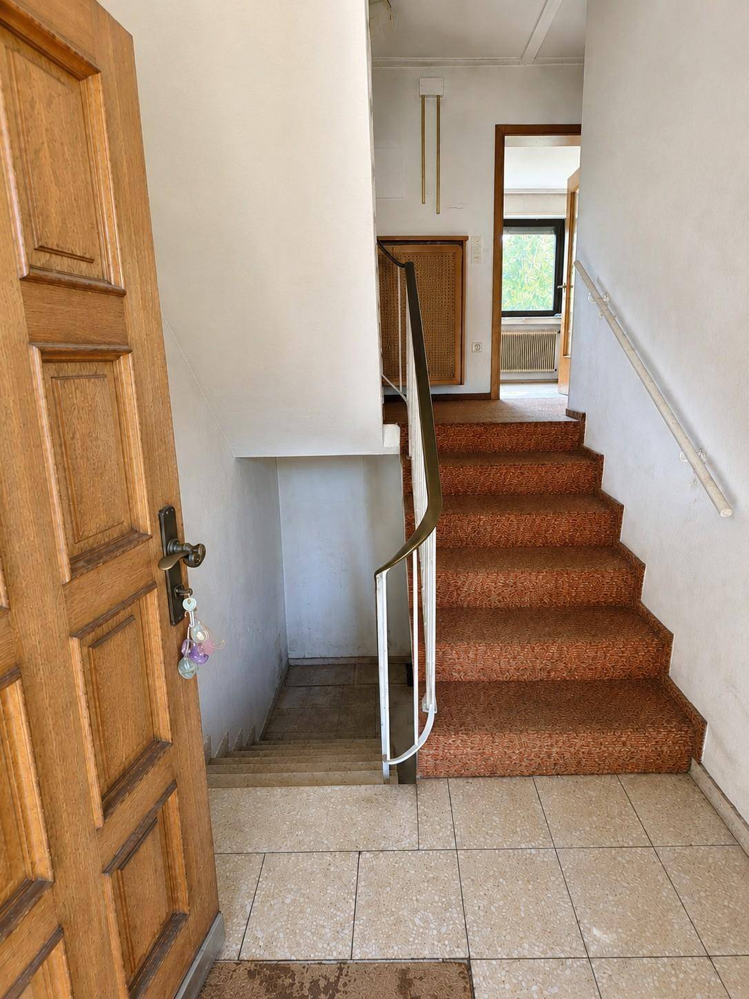 Eingangsbereich mit Fliesenboden und einer Treppe, die nach oben und unten führt.
