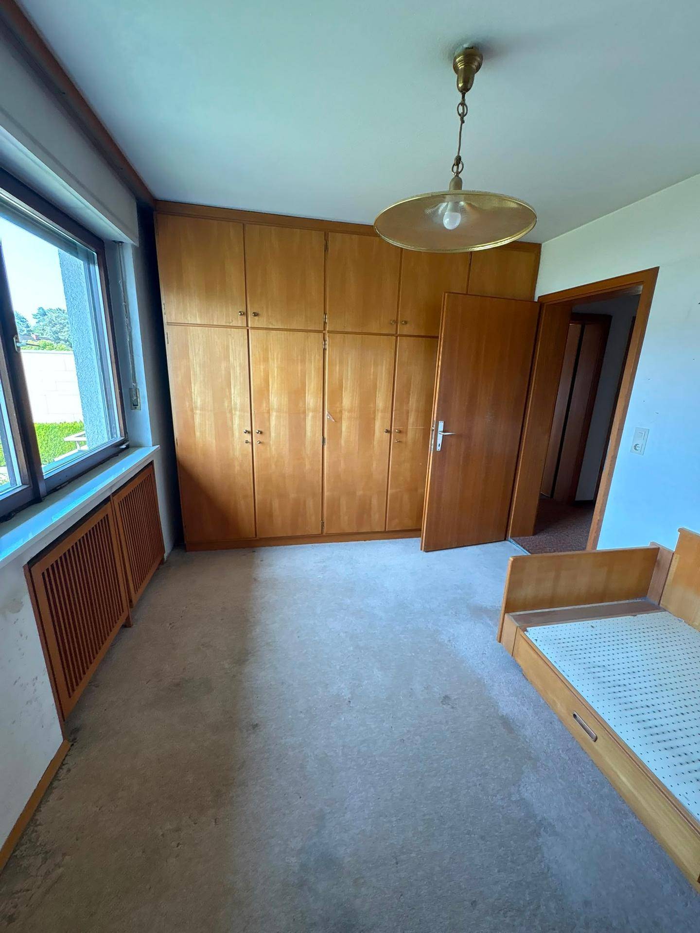 Schlafzimmer mit Teppichboden, eingebautem Holzschrank und Einzelbett.