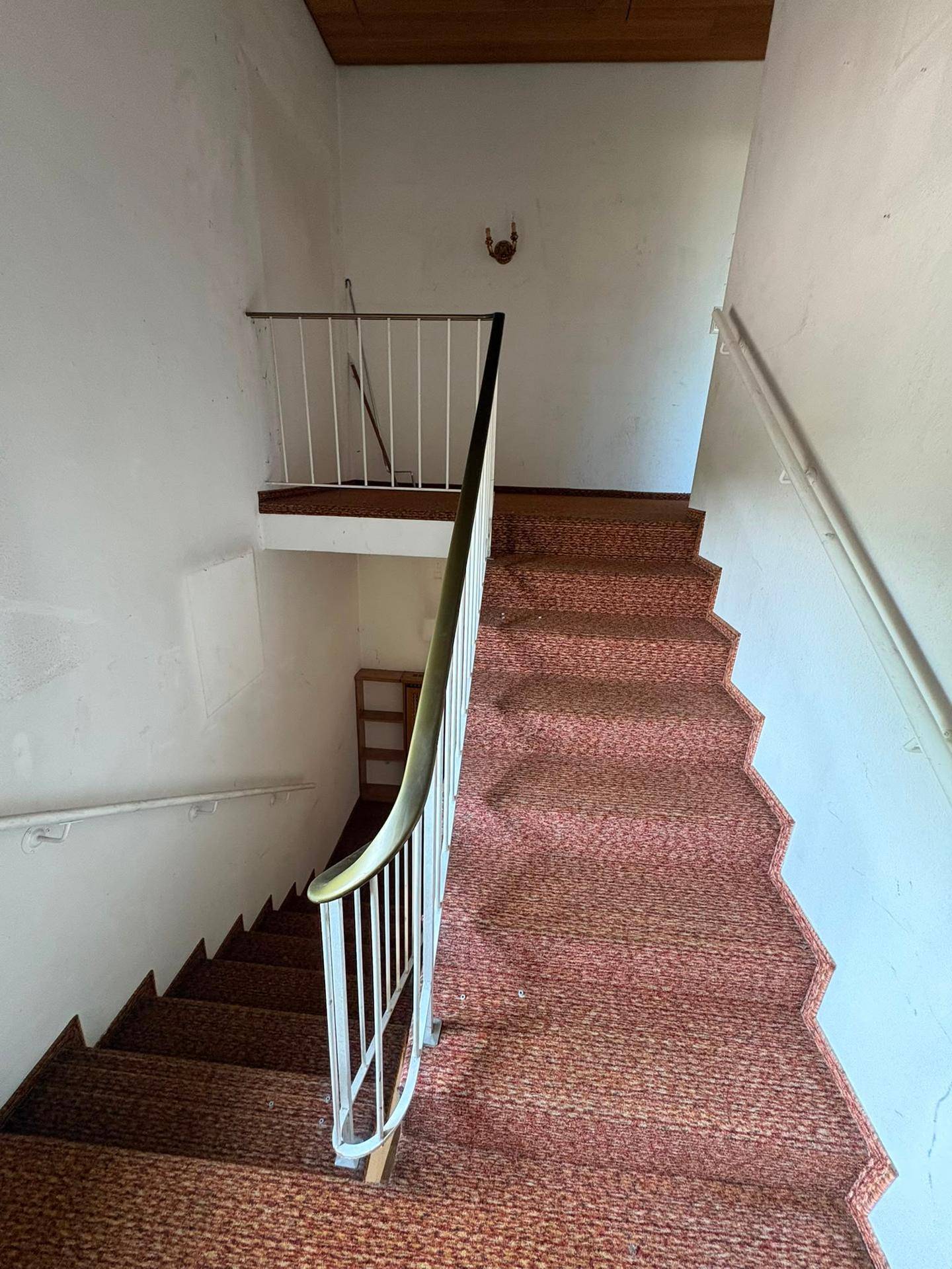 Innenansicht des Treppenhauses mit Teppichboden und klassischem Geländer, verbindet die Etagen.