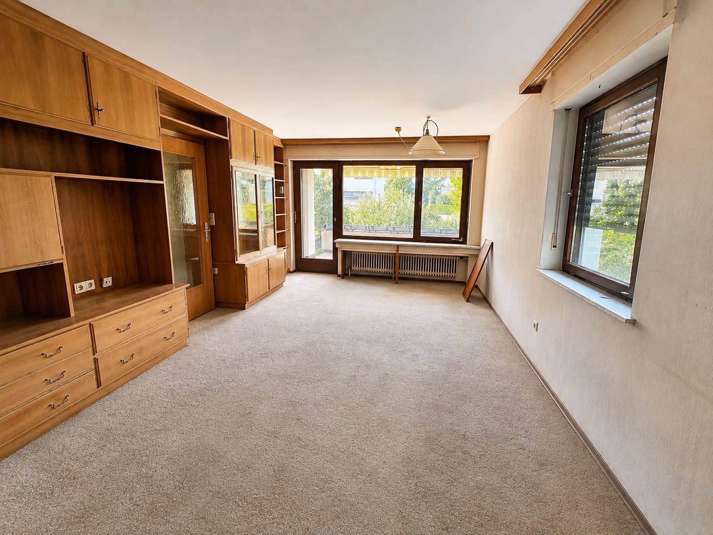 Helles Wohnzimmer mit Teppichboden und Holzmöbeln, bietet viel Platz für individuelle Gestaltung.