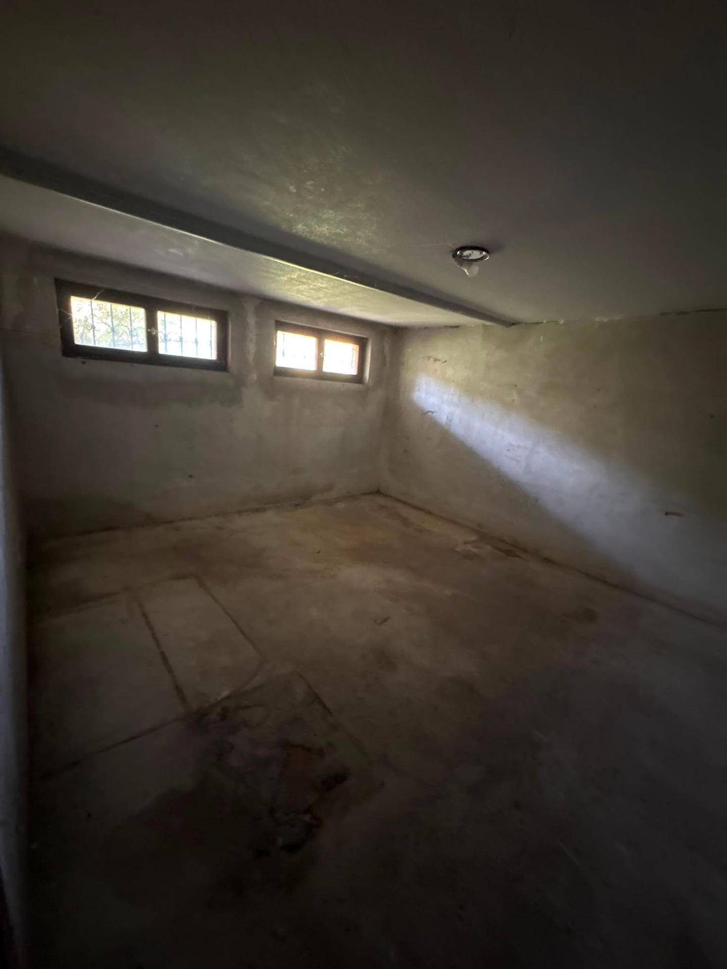 Unausgebauter Kellerraum mit Betonboden und kleinen Fenstern für Tageslicht.