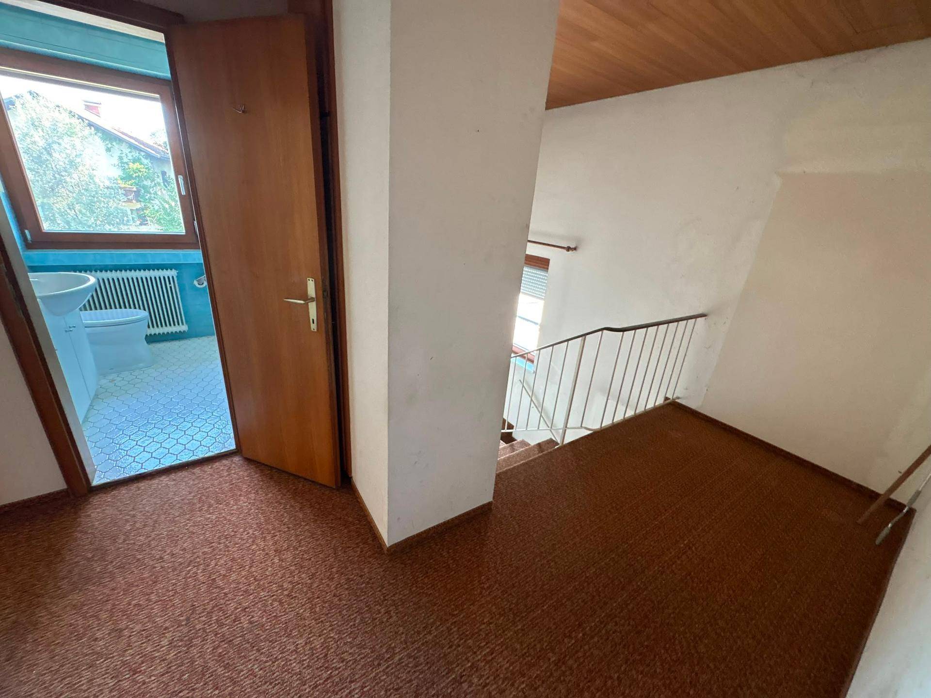 Flur mit Teppichboden, der zum Badezimmer und einer Treppe führt.