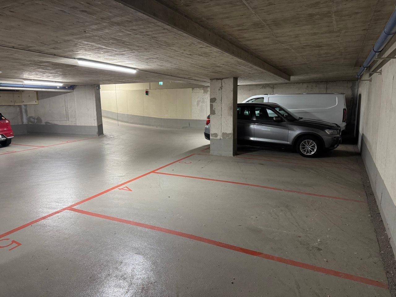Geräumige Tiefgarage mit mehreren Stellplätzen, Betonpfeilern und guter Beleuchtung.