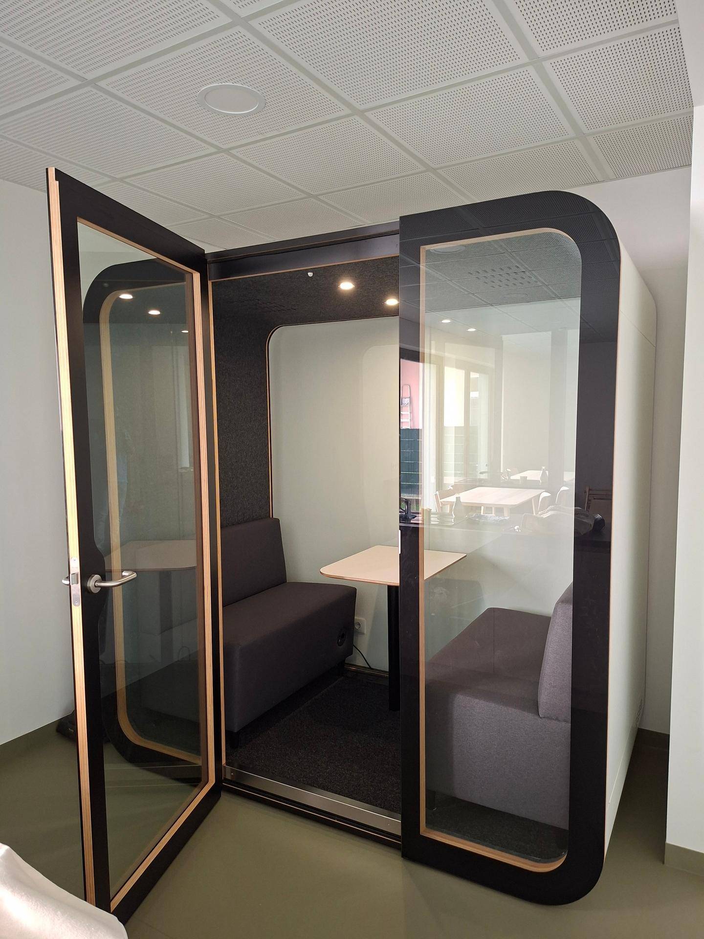 Moderne schallisolierte Kabine mit Sitzgelegenheiten und Tisch, ideal für konzentriertes Arbeiten.