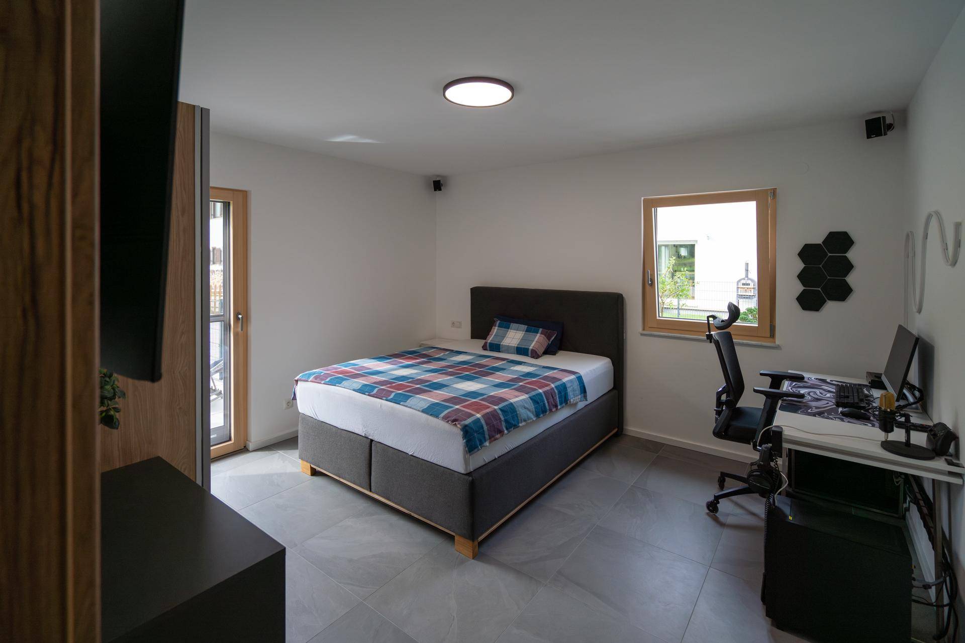Helles Schlafzimmer mit Einzelbett, Schreibtisch und Fenster für viel Tageslicht.