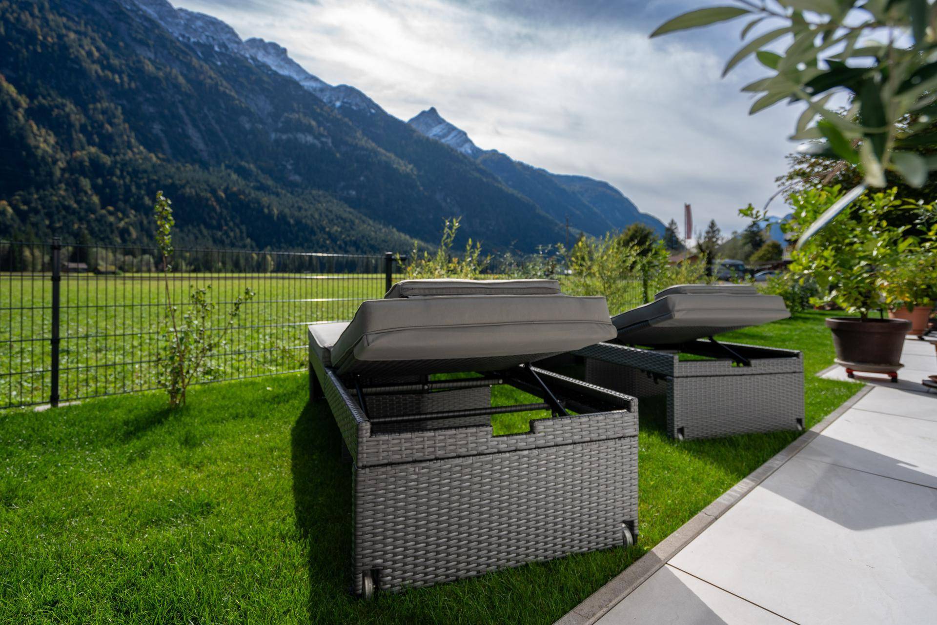 Entspannungsbereich im Garten mit Liegestühlen und weitem Blick auf die Berge.
